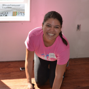 woman wearing pink in home with hammer smiling