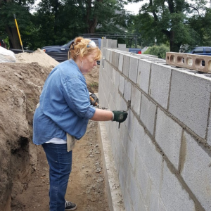 woman putting mortar between cinder blocks of a new home foundation